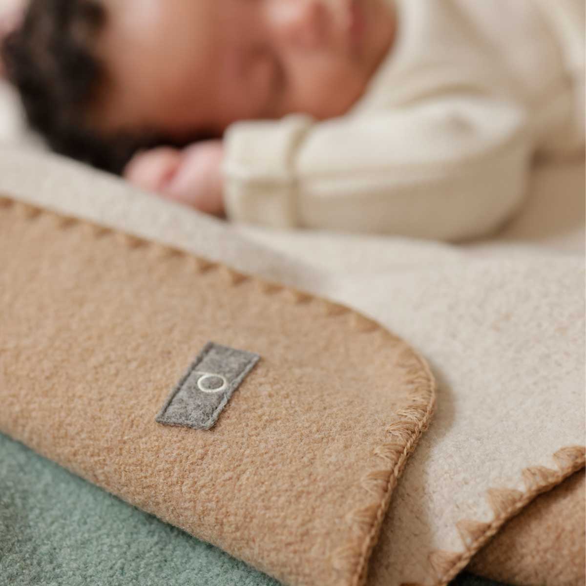Baby sleeping on a wool blanket with a disana label