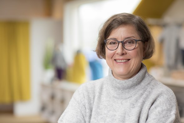 Porträt der disana Mitarbeiterin Regine Schindler im hellen Rollkragenpulli, lächelnd im disana Laden in Holzelfingen