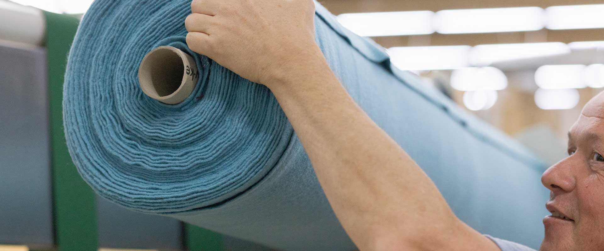 Employee with a fabric roll in disana production
