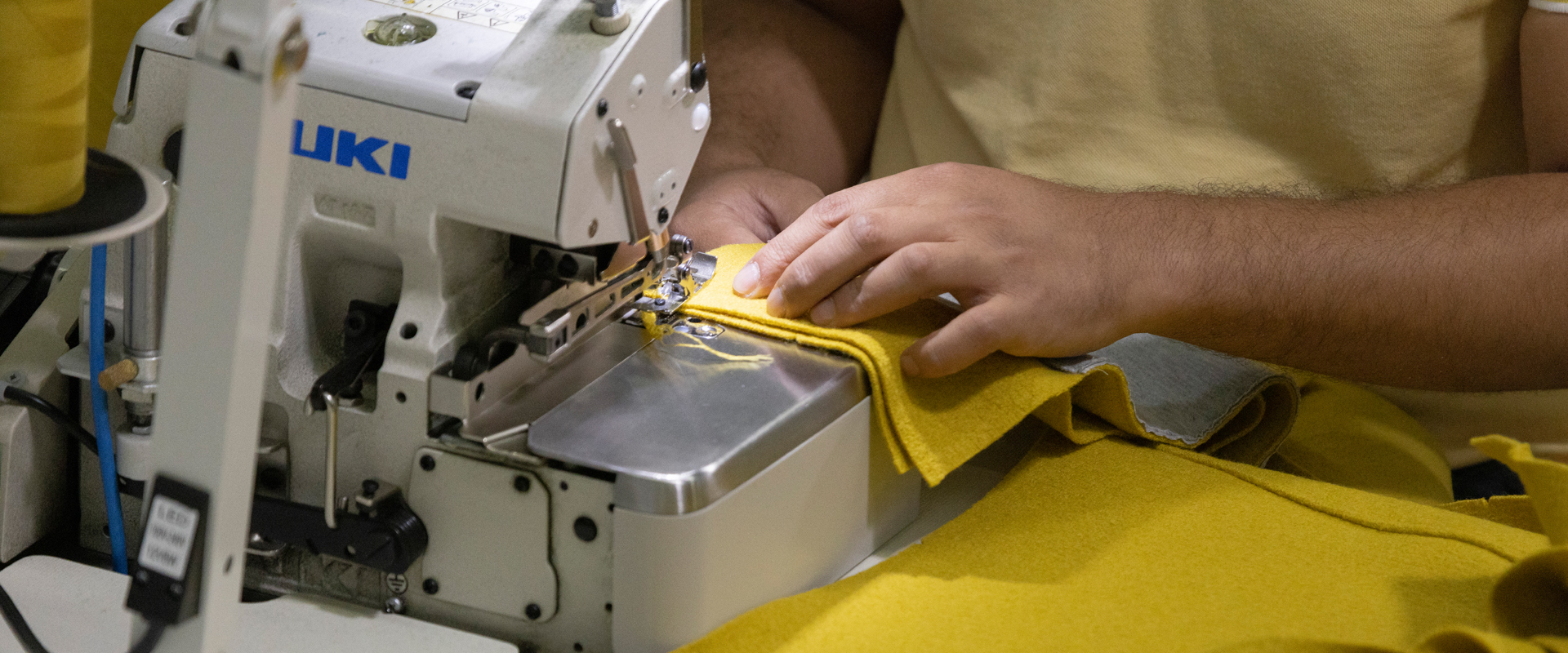 Yellow wool fabric being sewn on an overlock machine