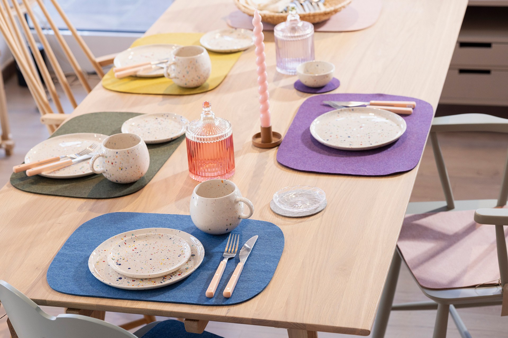 Bunt gedeckter Holztisch mit disana Filz-Tischsets aus Woll-Recyclingfilz, 100% Bio-Merinowolle, gesprenkeltem Geschirr